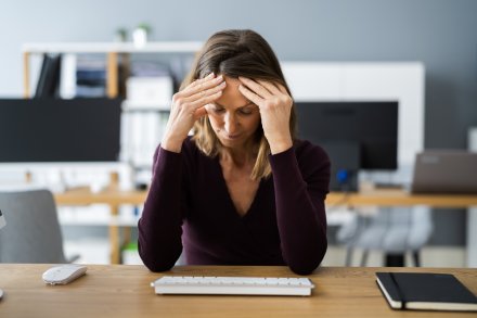 Woman holding head at her desk